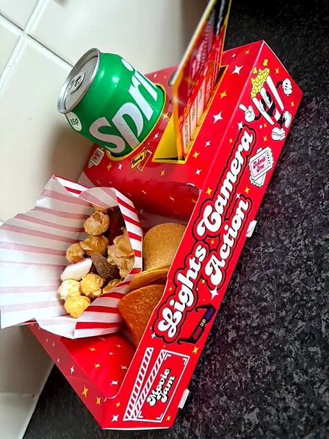 Red snack tray holding a can of Sprite, crisps and popcorn snacks