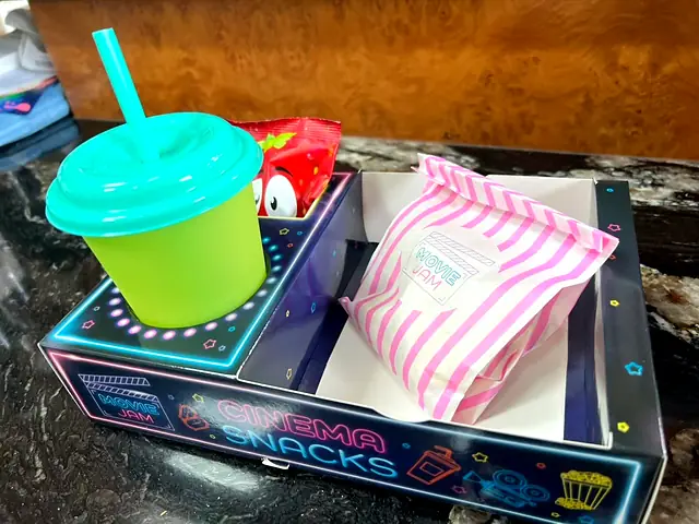 Neon Cinema Snacks tray with a green cup and striped sweet bag