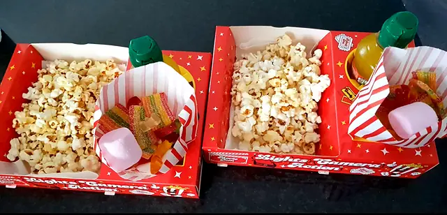 Two red snack trays filled with popcorn and sweets
