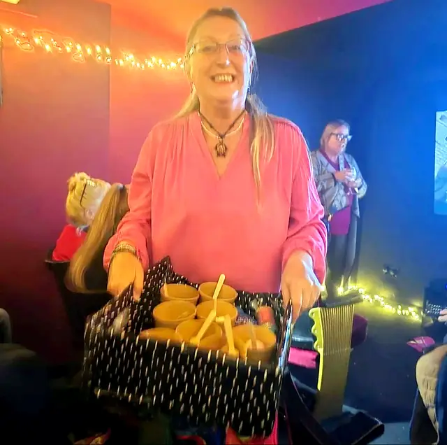 Smiling woman holding a tray of snacks in a home cinema room