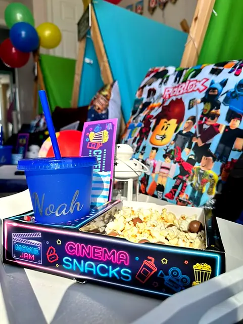 Personalised blue cup and neon Cinema Snacks tray at a Roblox sleepover