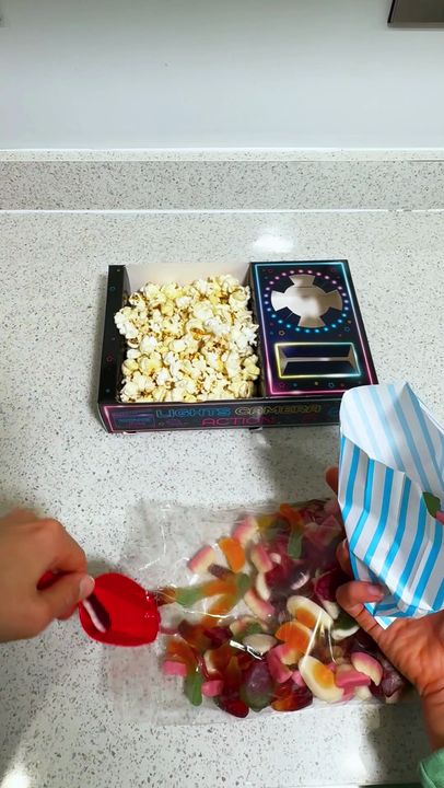 Hands unbox a Movie Jam kit, fold a neon tray and fill it with popcorn